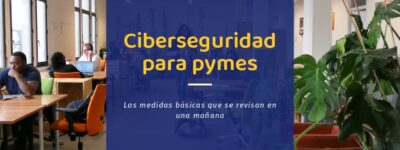 Ciberseguridad para pymes: puestos de trabajo con portátiles en una oficina abierta, con gente trabajando y una persona que cruza el pasillo con un café