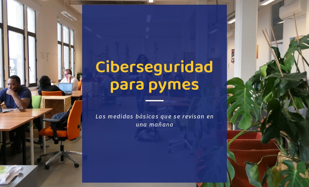 Ciberseguridad para pymes: puestos de trabajo con portátiles en una oficina abierta, con gente trabajando y una persona que cruza el pasillo con un café
